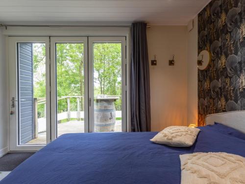 a bedroom with a blue bed and a sliding glass door at La Cafoutche de Minus rénovée 2pers in Gommenecʼh