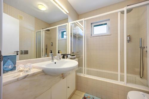 a white bathroom with a sink and a shower at V-Blue in Alvor