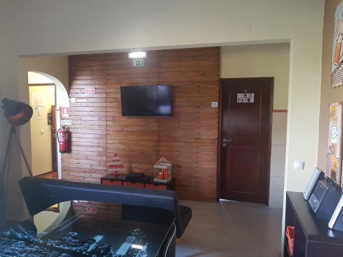 a room with a wooden wall with a television on it at Almancil Hostel in Almancil