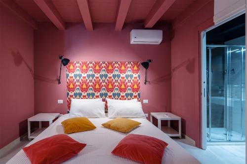 a bedroom with a large bed with red walls at Ortigiadreamrooms 12 in Syracuse