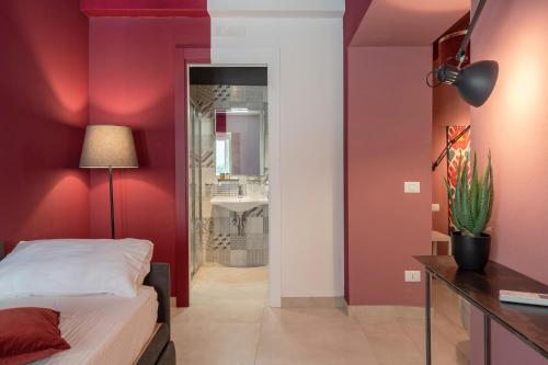 a bedroom with red walls and a bed and a bathroom at Ortigiadreamrooms 12 in Syracuse