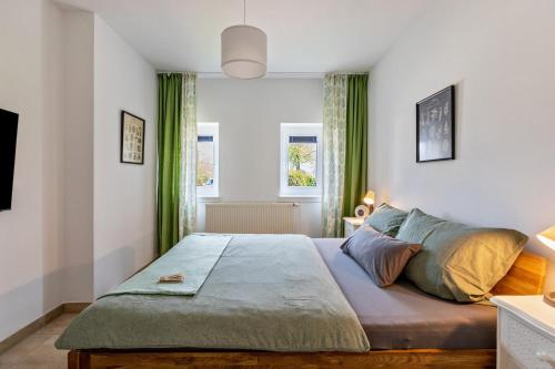 a bedroom with a large bed with green curtains at Gartenglückchen in Lindhöft