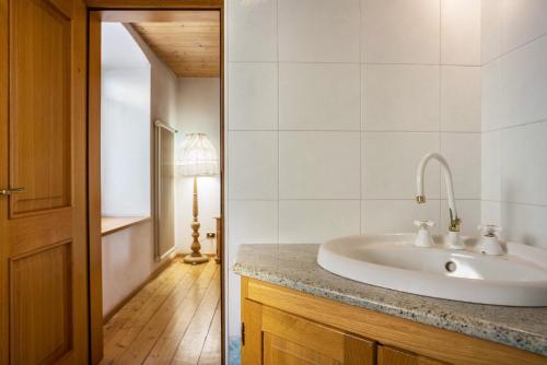 a white bathroom with a sink and a hallway at Casa Delmarco in Castello di Fiemme