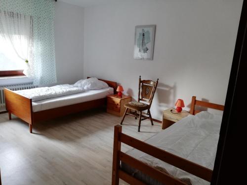 a bedroom with two beds and a chair in it at Luitje Gasthuus in Krummhörn