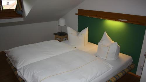 a bedroom with a white bed with a green wall at Haus Elbrächter Ferienwohnung 2 in Gstadt am Chiemsee