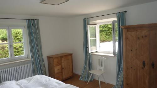 a bedroom with a bed and two windows at Haus Elbrächter - Erdgeschoss in Gstadt am Chiemsee