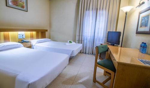 a hotel room with two beds and a desk and a television at Pacoche Murcia in Murcia