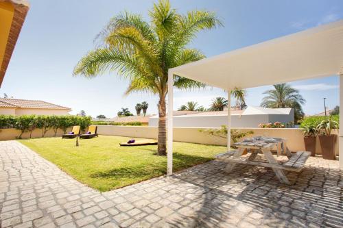 a patio with a picnic table and palm trees at Retiro Praia in Campo de Baixo