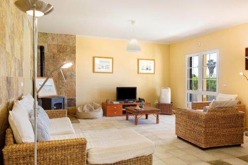 a living room with a couch and a tv at Retiro Praia in Campo de Baixo