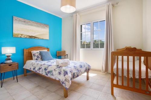 a bedroom with blue walls and a bed and a window at Retiro Praia in Campo de Baixo