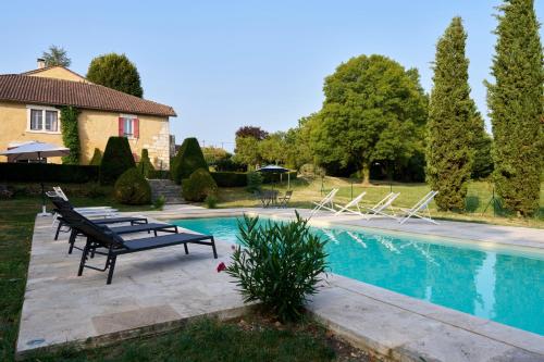 una piscina con bancos al lado de una casa en La Bastide 24, en Chapdeuil