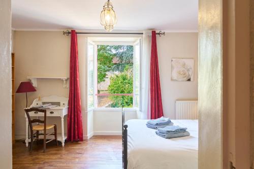 un dormitorio con una cama, un escritorio y una ventana en La Bastide 24, en Chapdeuil