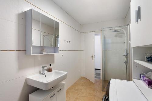 a white bathroom with a sink and a shower at Ferienwohnung Cakir in Meinerzhagen