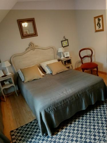 a bedroom with a large bed and a red chair at Chambres D'hôtes Au Gré Du Temps in Saint-Aignan