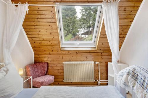 a attic bedroom with a window and a chair at Haus Antonis in Triberg