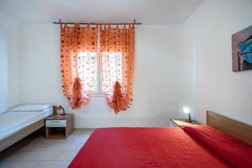 a bedroom with a bed and a window with an orange rug at Appartamento Andromeda B4 in Bibione