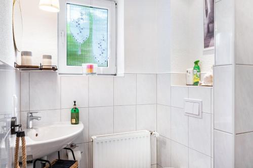 a white bathroom with a sink and a window at Ferienhaus Franz in Jemgum