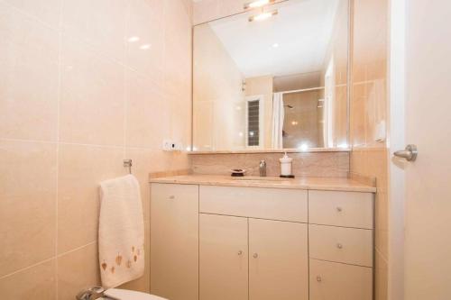 a bathroom with a sink and a toilet and a mirror at Maresme Beach Apartment in Canet de Mar