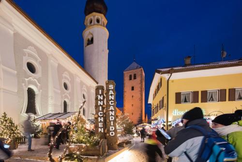 a group of people walking down a street with a clock tower at Dolomite Apartments - by Familiaris in San Candido