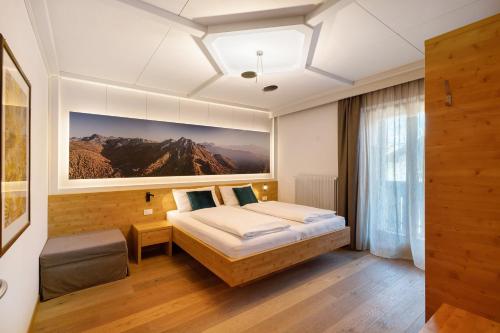 a bedroom with a bed and a large painting on the wall at Kriendl Nr 1 in Valdaora