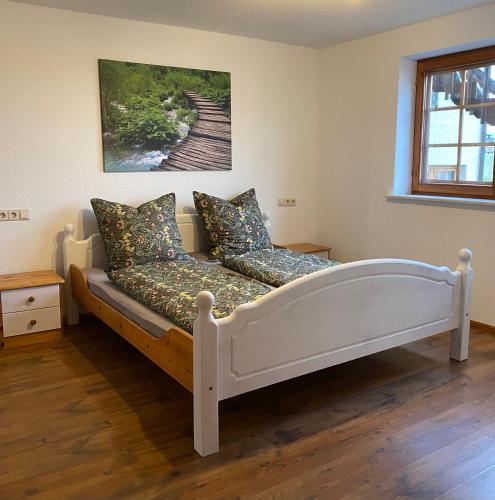 a white bed in a room with a painting on the wall at Schwarzwaldnest Dachsberg in Wilfingen