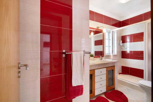 a red and white bathroom with a toilet and a shower at Ideal Villas Residence in Vila Nova De Cacela