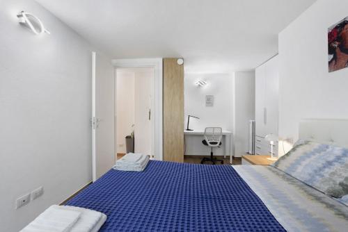 a white room with a blue bed and a desk at Suite Strada Persa in Pavia