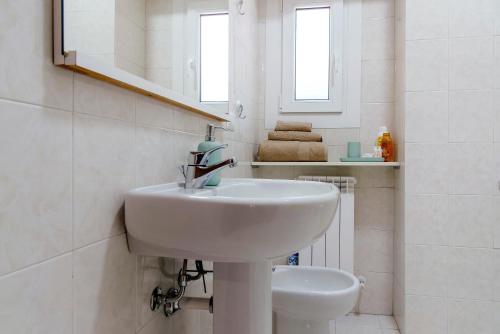 a white bathroom with a sink and a mirror at Casa Maria in Porto Ceresio