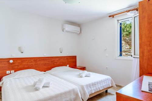 a bedroom with two beds with white sheets and towels at Anemologio 301 Tinos in Agios Ioannis