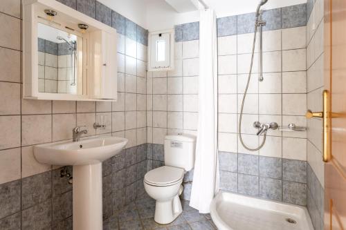 a bathroom with a toilet and a sink and a shower at Anemologio 301 Tinos in Agios Ioannis