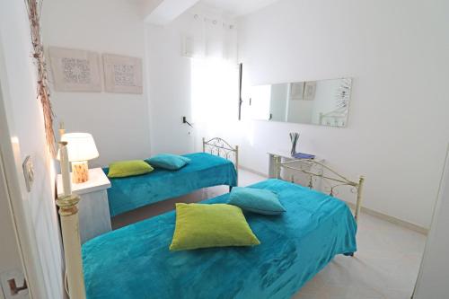 two beds in a room with blue sheets at Casa Primus Torre Santo Stefano in Otranto
