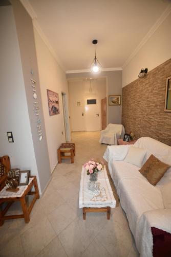 a living room with a white couch and flowers on a table at Nicol apartment in Koustáros