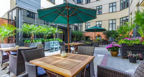 an outdoor patio with tables and chairs and an umbrella at Best Western Hotel Hebron in Copenhagen
