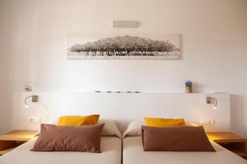 a bed with two pillows and a painting on the wall at Vivendes Adelina - Escapada Formentera in Es Pujols