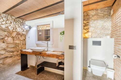 a bathroom with a sink and a stone wall at El Cobert De Lera in Oden