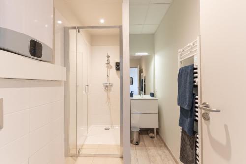 a white bathroom with a shower and a sink at Viognier - logement avec jacuzzi in Ruoms