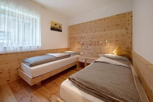 two beds in a room with a wooden wall at Teutenhofer Apfel in Feldthurns