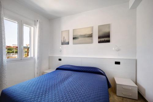 a white bedroom with a blue bed and two windows at Antichi Ricordi - Il Pollaio in Marina di Andora
