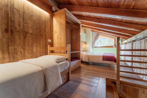 two beds in a room with wooden walls at Civico 2 in Marmora