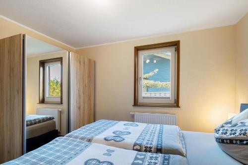 a bedroom with two beds and two windows at Ferienhäuser Hainichhöhe in Hörselberg-Hainich