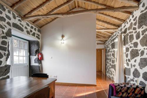 a living room with a stone wall and a table at Adega Maciel in Lajido
