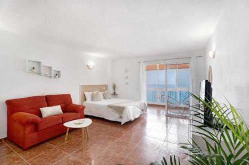 a living room with a red couch and a bed at Apartamento Luna in Tacoronte