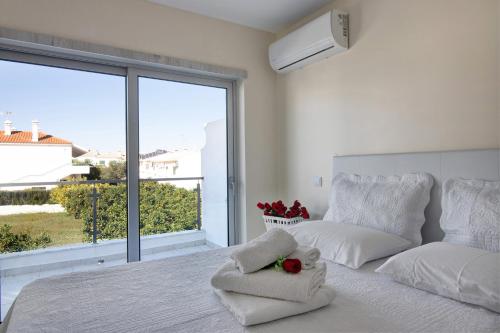 a white bedroom with a bed and a large window at Numar Residence Villa X in Manta Rota