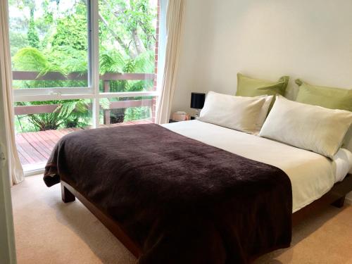 a bedroom with a large bed with a large window at Wildwood Lodge in Belgrave