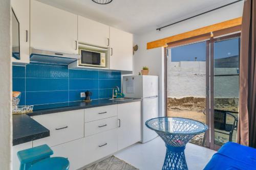 a kitchen with white cabinets and blue tiles at Loft La Caletilla La Graciosa in Caleta de Sebo