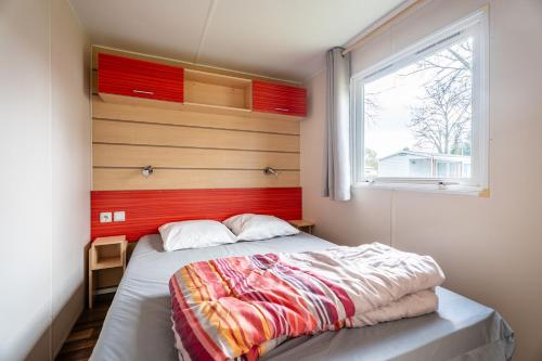 a bedroom with a bed with a red headboard and a window at Euro Mobil B16 in Boofzheim