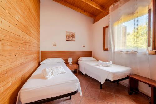 two beds in a room with a window at Agriturismo Alimini a Otranto in Alimini