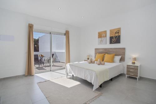 a white bedroom with a large bed and a balcony at Casa Gara Fuerteventura in Gran Tarajal