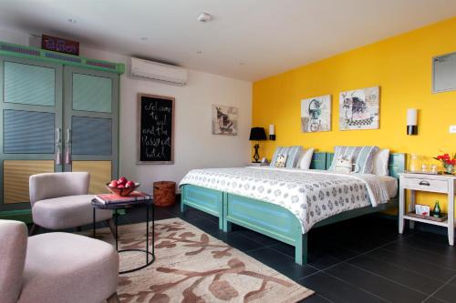 a bedroom with a bed and a yellow wall at Owl and the Pussycat Hotel & Restaurant in Unawatuna