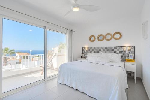 a white bedroom with a bed and a large window at La Perla in Callao Salvaje